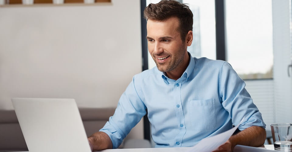 Man working on laptop with a light blue button-down shirt